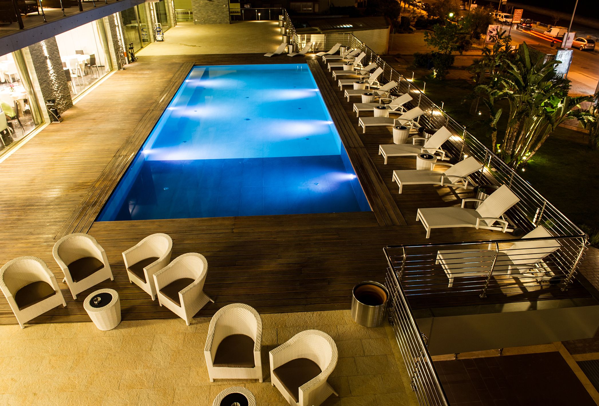 A rooftop pool with lounge chairs and a bar area.