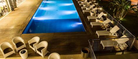 A rooftop pool with lounge chairs and a bar area.