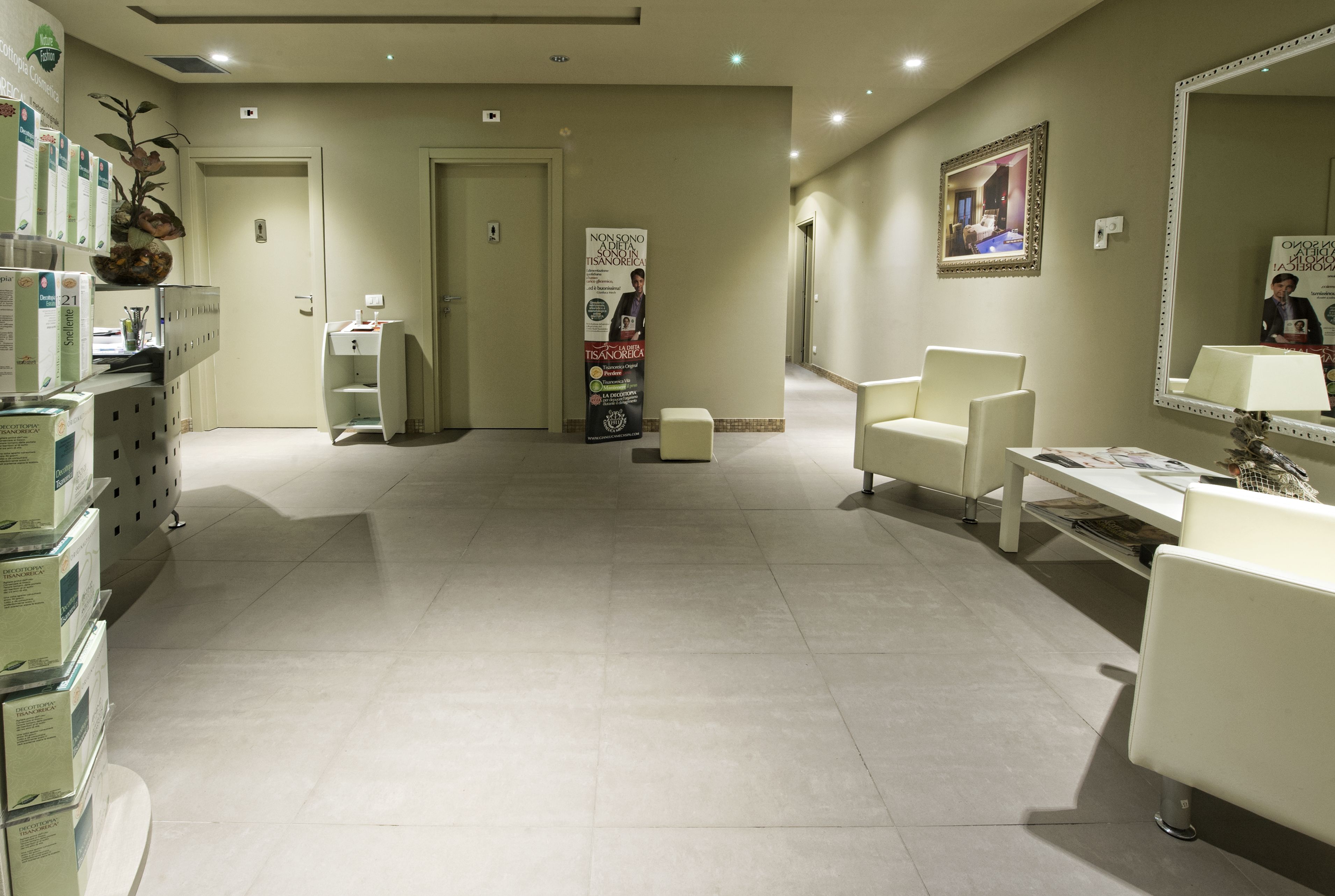 Un hall de hotel con mostrador de recepción, zona de estar y un espejo grande.