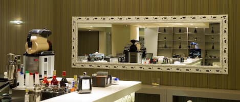 A hotel bar area with a large mirror, bar counter, and shelves of bottles.