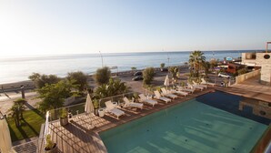 Une piscine sur le toit, dotée de chaises longues et offrant une vue sur la mer.