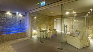 Un espace spa moderne avec un mur en pierre, un espace de détente clos par des parois de verre et un panneau de signalisation indiquant la sortie.