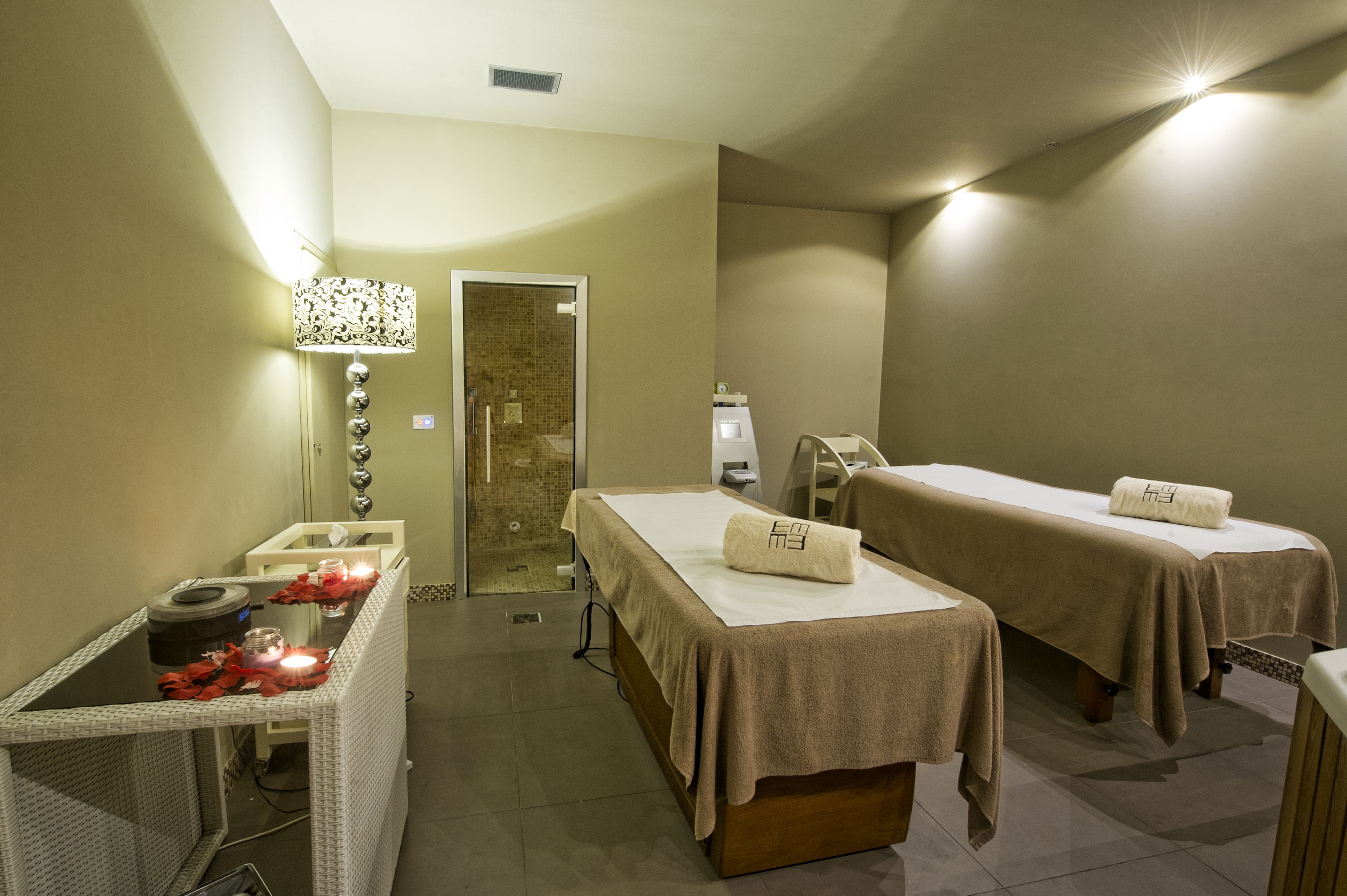 A spa room with two massage tables, a reception area, and a shower.