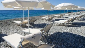 Une plage avec des parasols blancs et des chaises longues disposés en rangées.