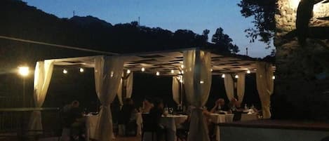 Un área de comedor al aire libre con mesas y sillas bajo una estructura cubierta.