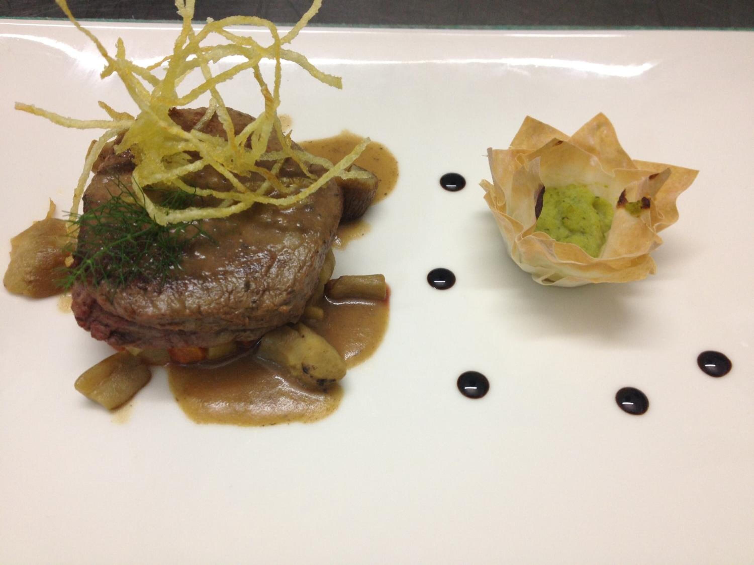 Un plato con filete, verduras y salsa.
