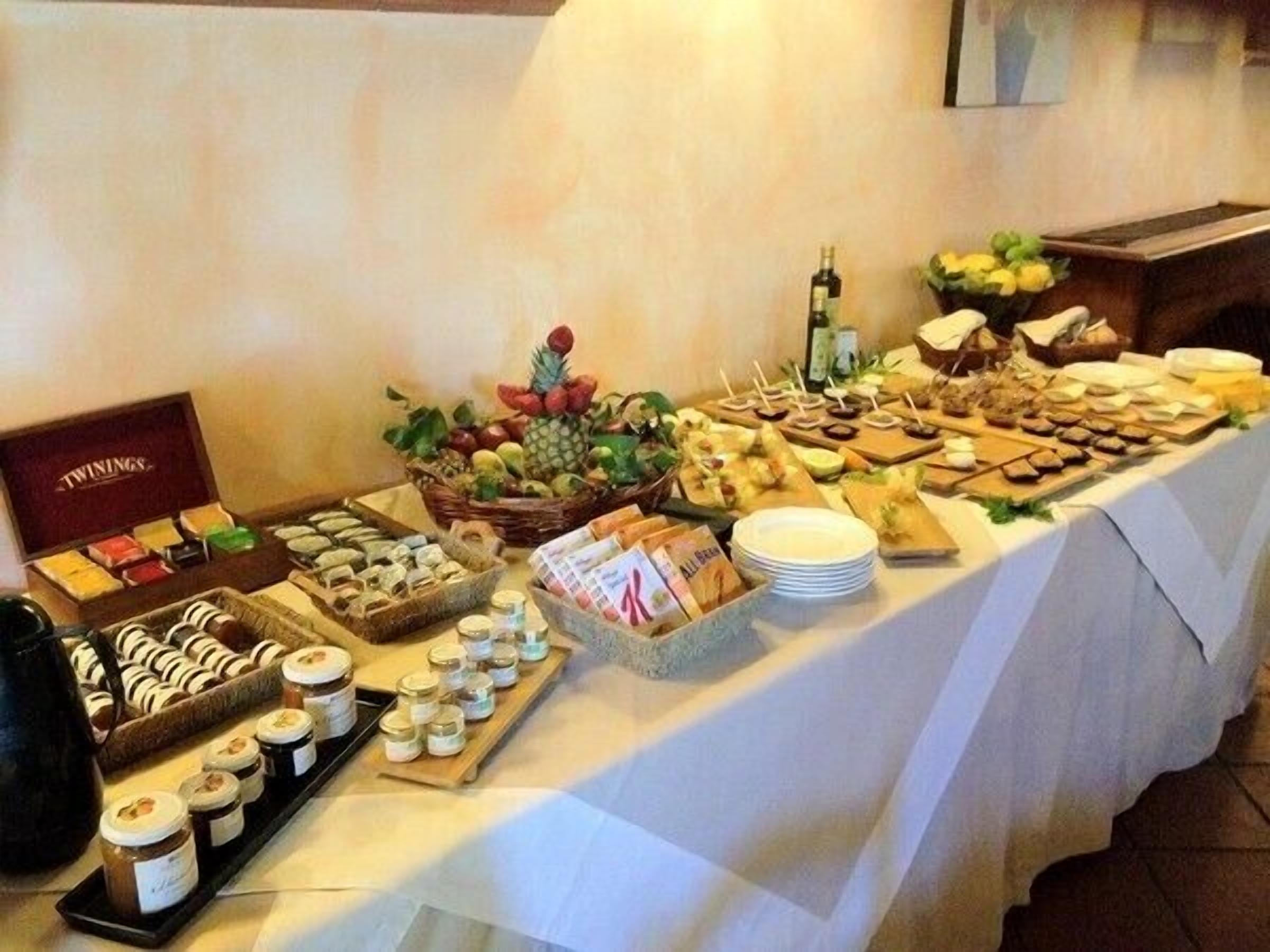Una mesa de bufé con diversos alimentos, como frutas, pasteles y salsas.