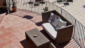 A rooftop terrace with a swimming pool, outdoor seating, and potted plants.