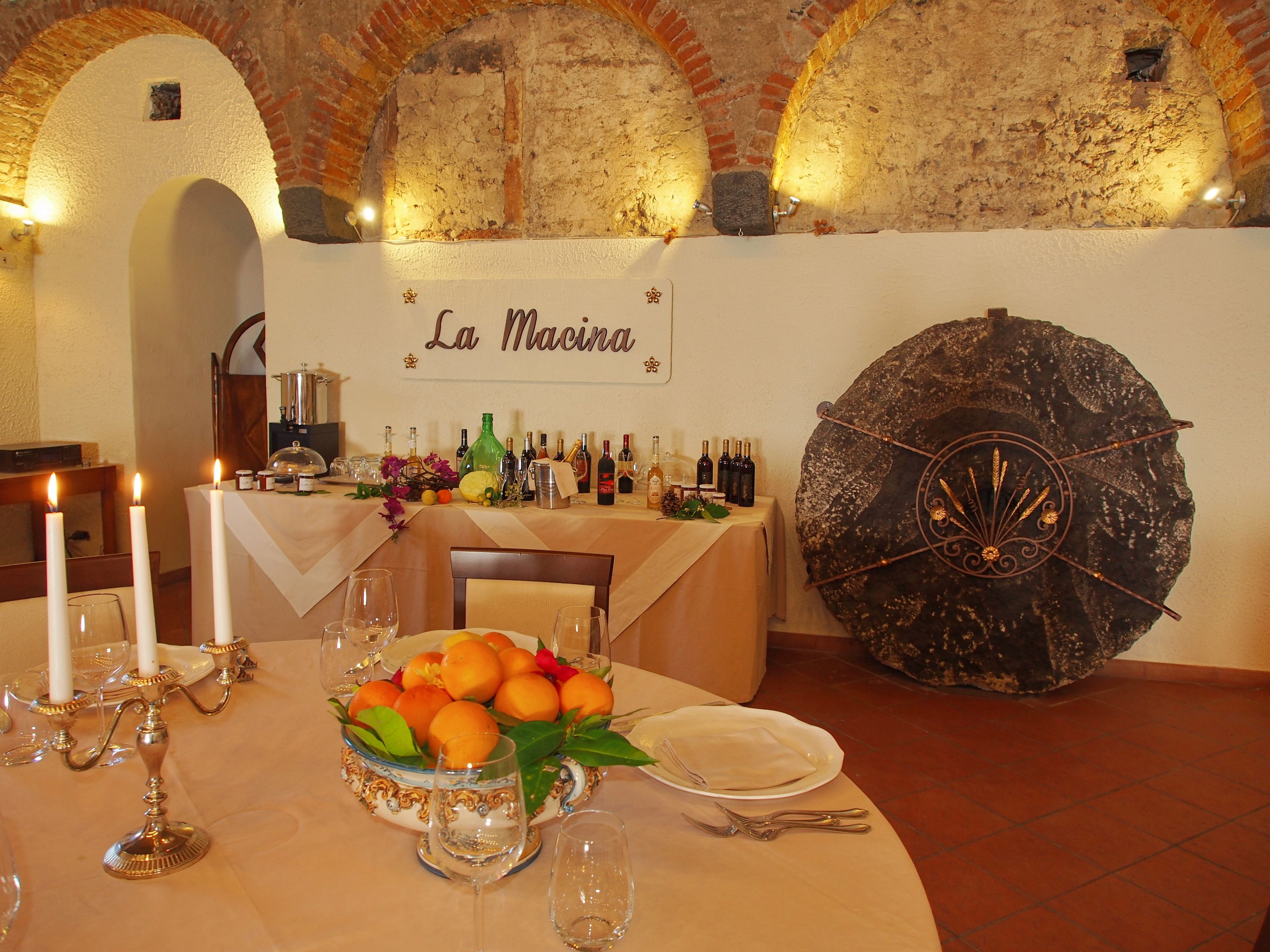 Una mesa de comedor adornada con velas, un frutero, botellas de vino y un paraguas decorativo grande.