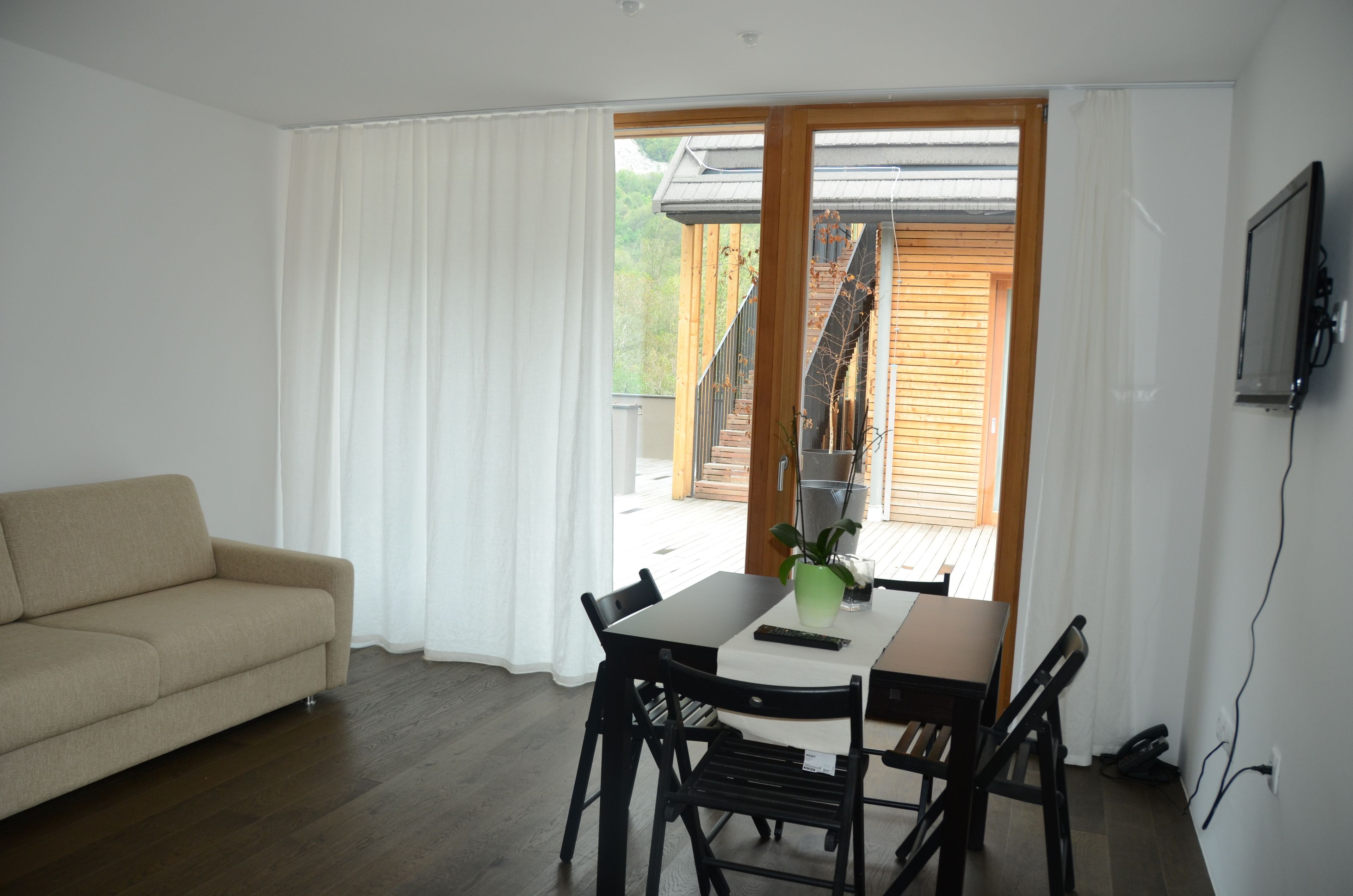 A modern living room with a sofa, dining table, chairs, and a TV.