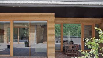 Un edificio moderno con grandes puertas correderas de vidrio y una terraza de madera.