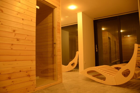 Interior de madera con un vidrio que da a una habitación oscura. Hay dos mecedoras de madera.
