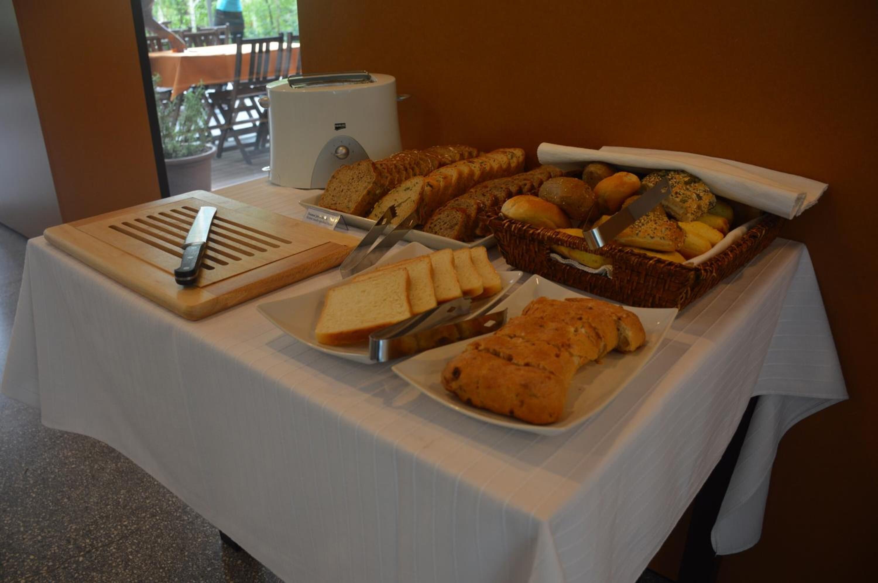 A buffet table with various breads, pastries, and a toaster.