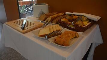 A buffet table with various breads, pastries, and a toaster.