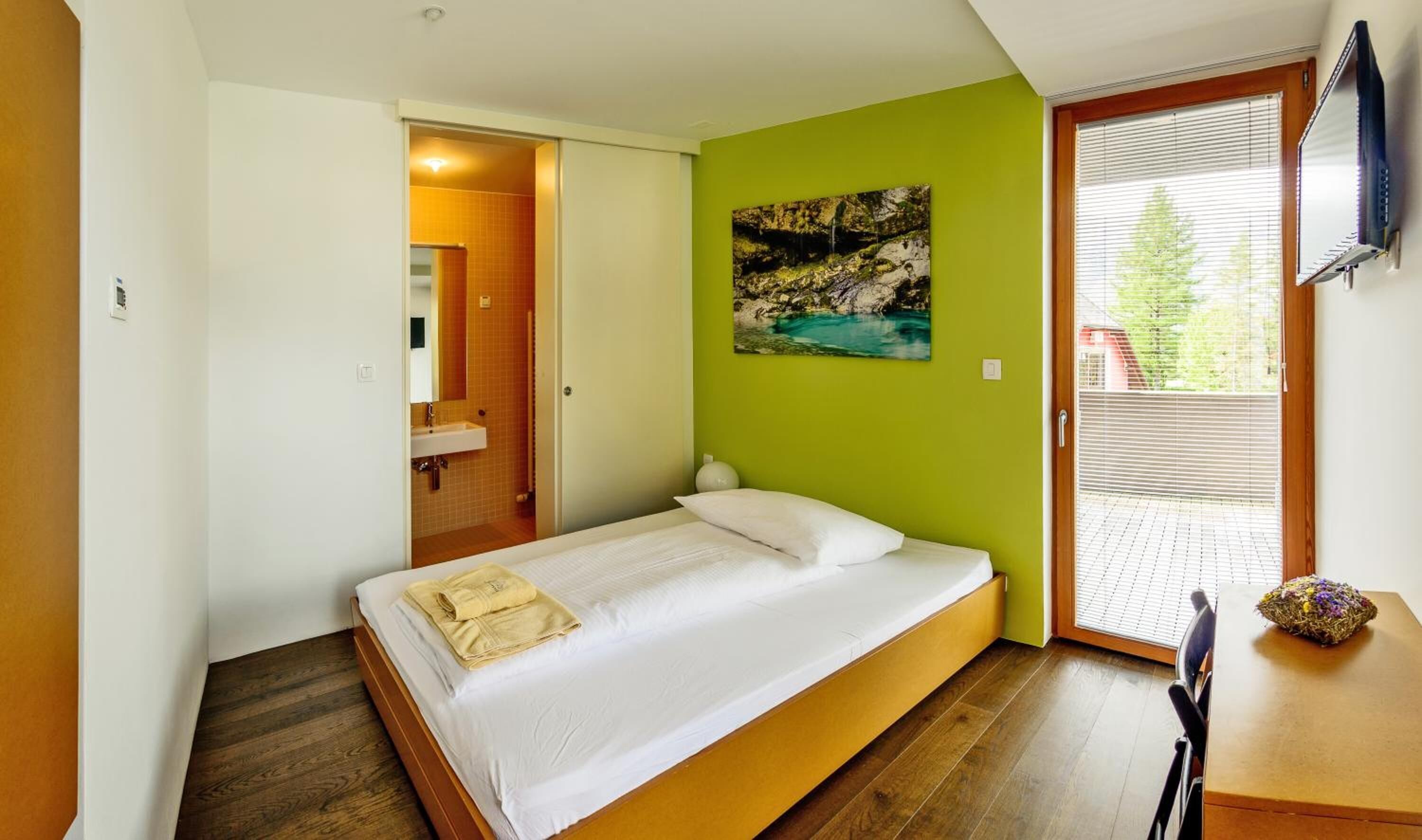 Quarto com cama, quadro, janela e porta para um banheiro.