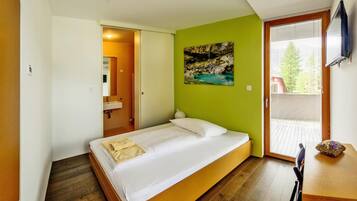 Quarto com cama, quadro, janela e porta para um banheiro.