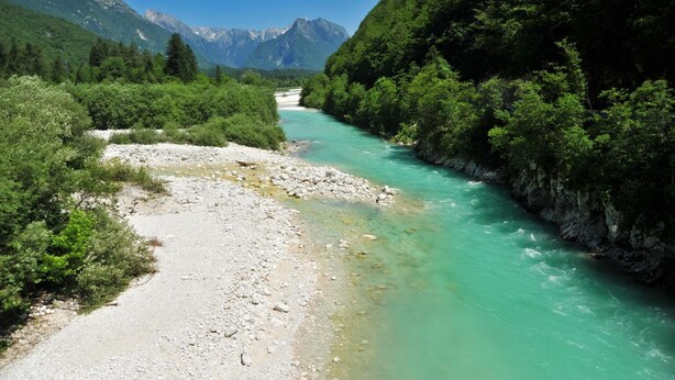 Un río serpentea a través de una zona montañosa, con abundante vegetación y terreno rocoso.