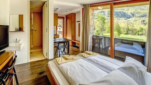 Habitación de hotel moderna con una cama grande, un escritorio con una silla, un televisor y un baño con ducha e inodoro.