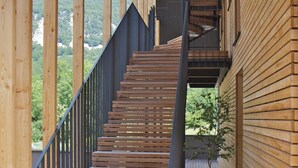 Una escalera de madera con barandilla metálica que lleva a un nivel superior.