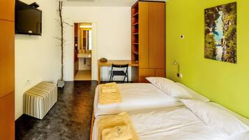 A hotel room with two beds, a desk, a TV, and a painting on the wall.