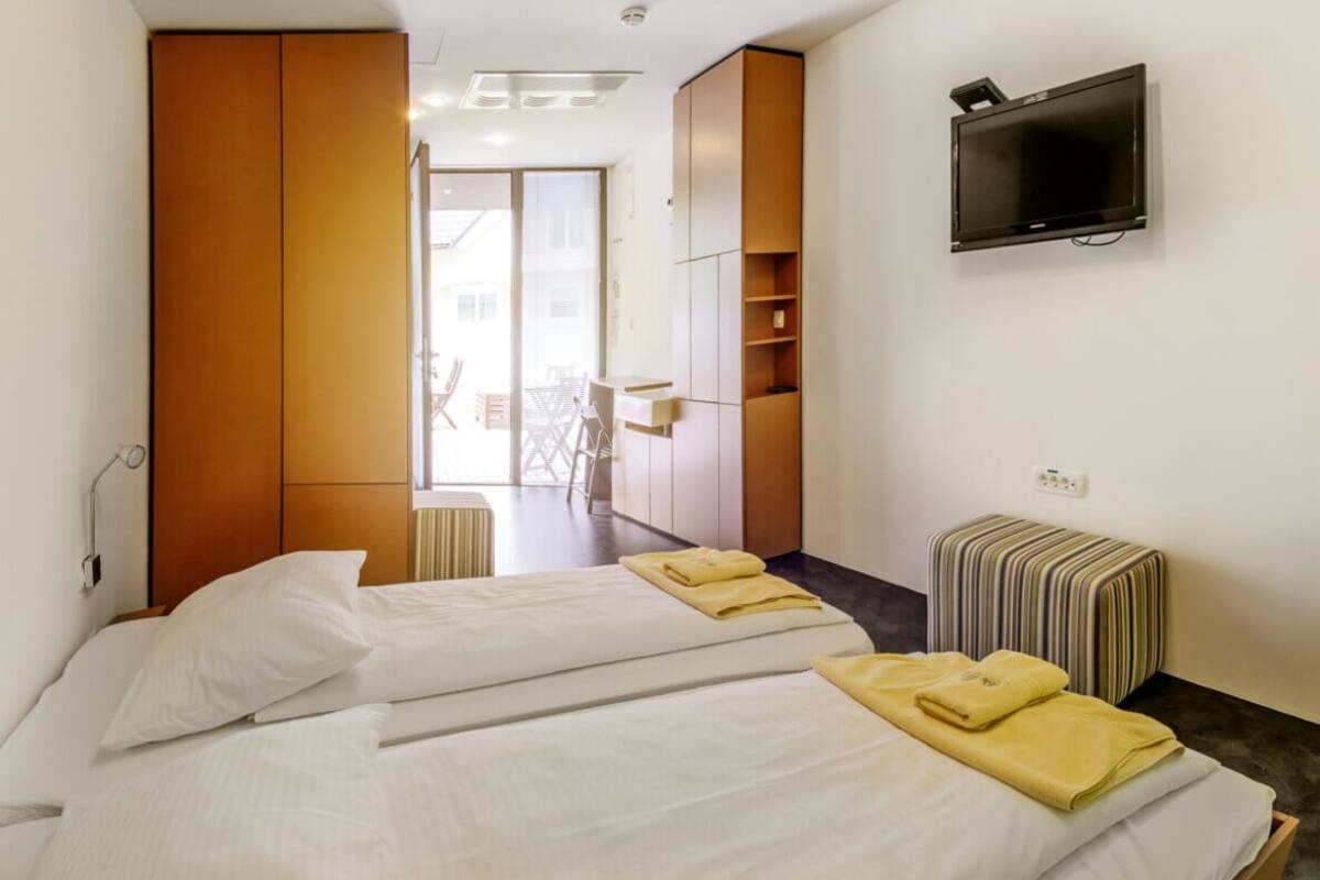 Une chambre d’hôtel avec deux lits, une télévision, une petite table et une vue sur l’extérieur.