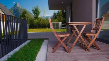 Eine moderne Außenpatio mit einem Holztisch und -stühlen, einem schwarzen Zaun und Blick auf die Berge.