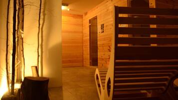 Un interior de madera con una zona de sauna, un banco de madera y una puerta que da a otra habitación.