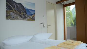 Un dormitorio con cama, puerta, ventana y un cuadro en la pared.