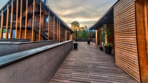 Un edificio moderno con fachada de madera, un espacio exterior cubierto con escalones, y plantas en macetas.