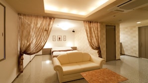 A hotel room with a bed, a sofa, a coffee table, and curtains.