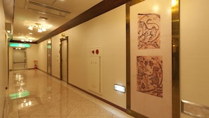 A hotel corridor with a polished floor, a fire alarm, and a wall-mounted artwork depicting a leopard.