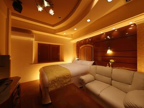A hotel room with a bed, a sofa, a desk, and a wardrobe.