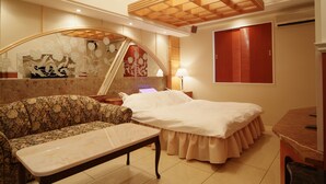 Una camera d'albergo con divano, un letto, una scrivania e uno specchio.