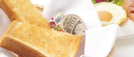 A basket containing a slice of toasted bread, a container of soft whipped butter, a plate with a fried egg, and a side salad.
