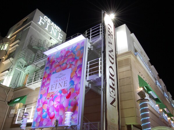 A building with a prominent 'GRAND FINE' sign, a large colorful advertisement, and a staircase with railings.