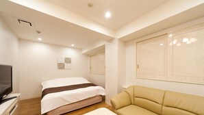 Una habitación de hotel con cama, sofá, televisión y una mesita.