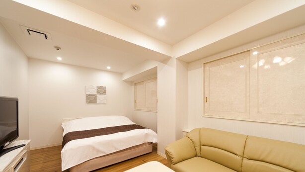 Une chambre d’hôtel avec un lit, un canapé, une télévision et une petite table.
