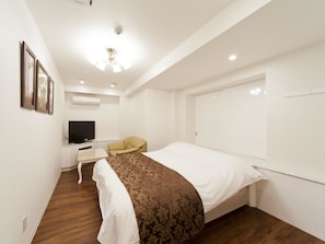 Una habitación de hotel con cama, escritorio con televisor, silla y armario.