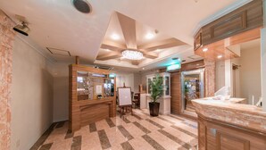A hotel lobby with a reception desk, a large chandelier, and a check-in counter. - Fine Tsu (Tsu)