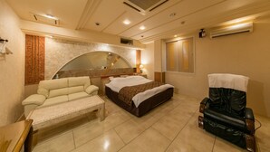 A hotel room with a bed, a massage chair, a sofa, and a small table. - Fine Tsu (Tsu)