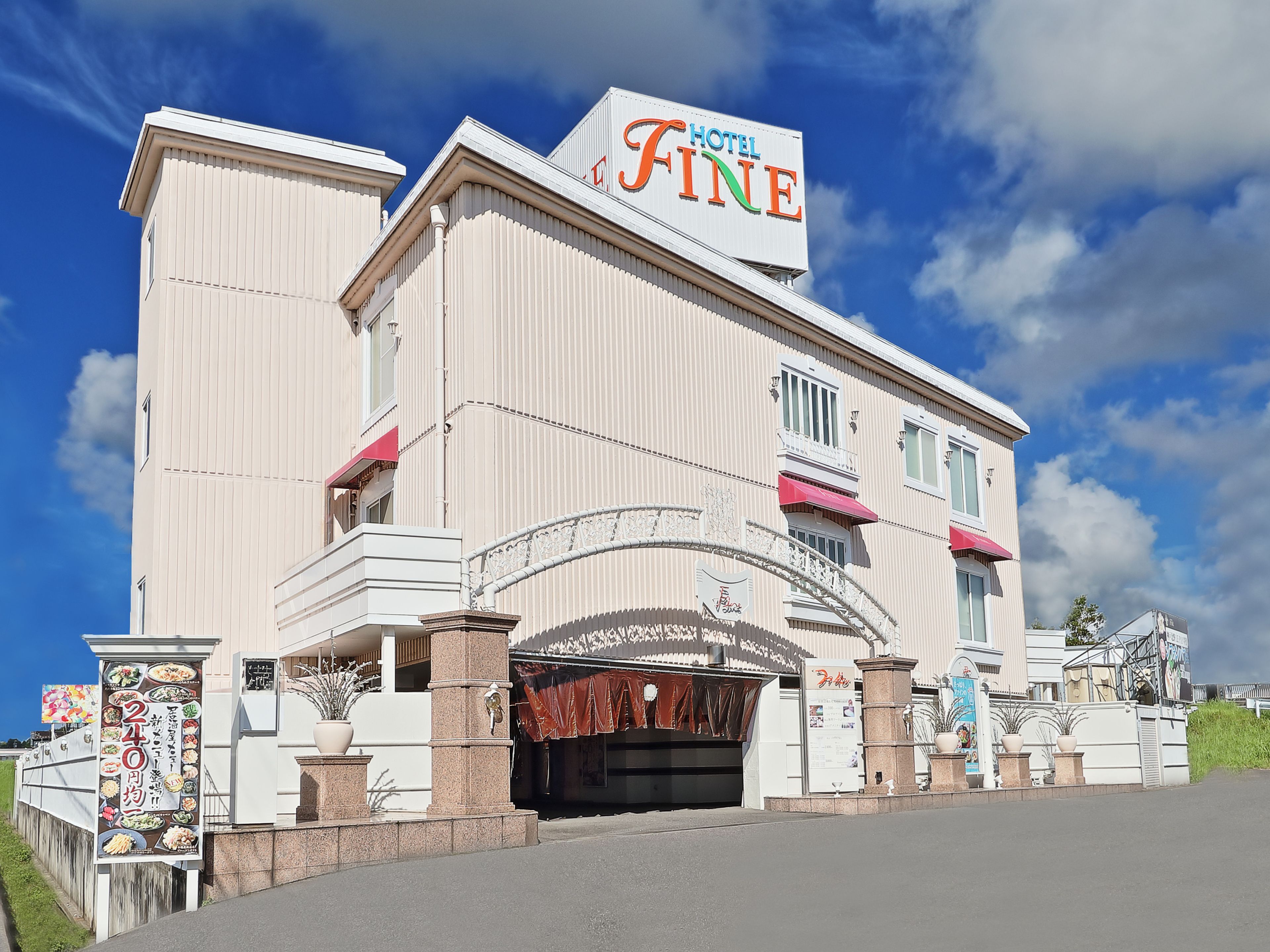 Un hotel con un cartel llamativo que dice "Hotel Fine" y una amplia entrada con un arco decorativo.