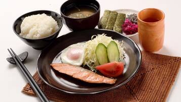 A plate with salmon, egg, cucumber, and tomato, accompanied by bowls of rice, soup, and pickled vegetables.