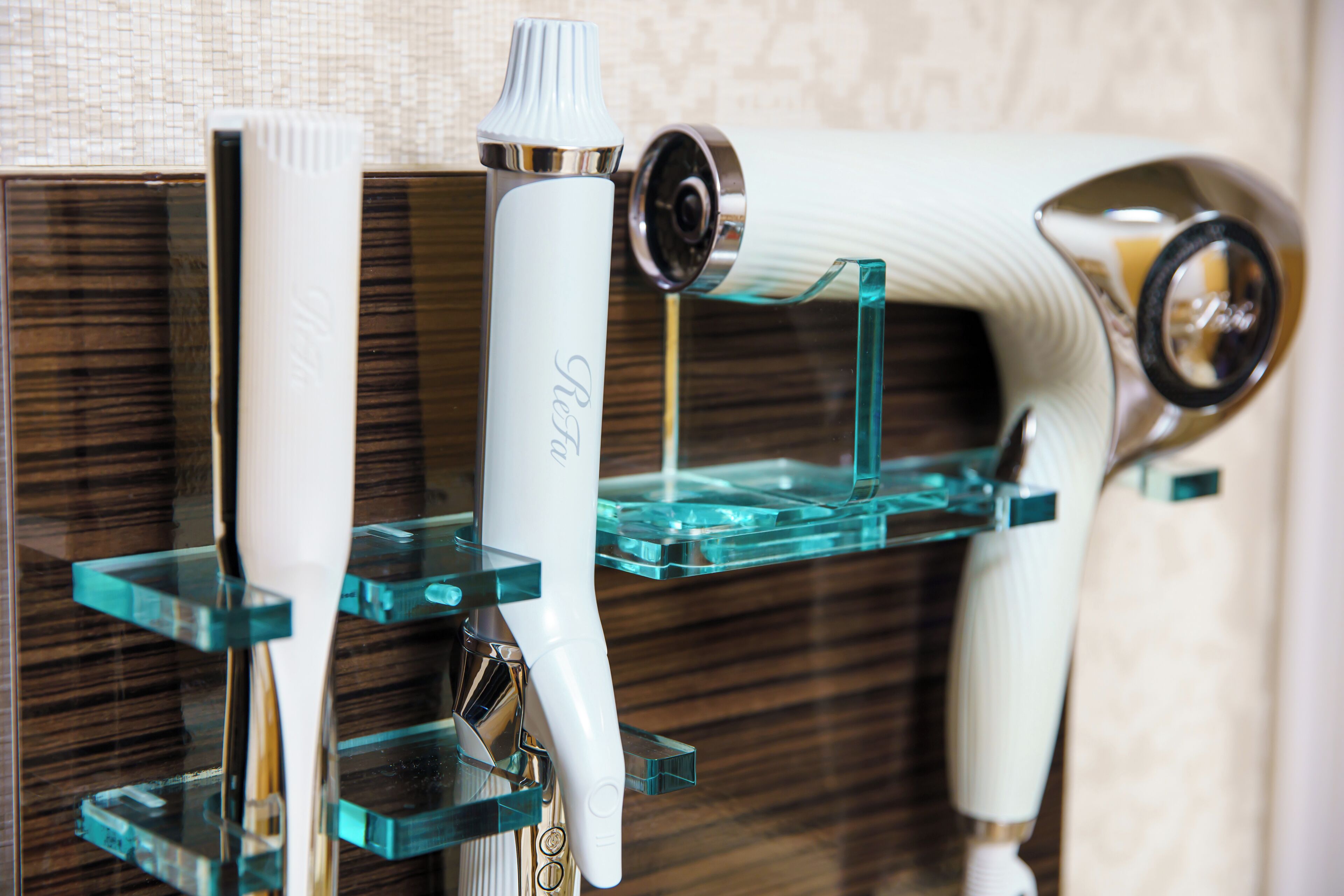 A bathroom with a modern design, featuring a glass shelf holding toiletries and a white electric toothbrush.