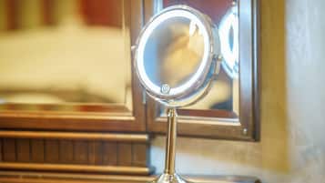 A round mirror with a light on a stand, placed on a wooden surface.