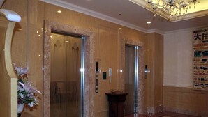 An elevator area with marble walls, a chandelier, and a flower arrangement. - Hotel Fine Garden Toyonaka Itami Airport (Toyonaka)