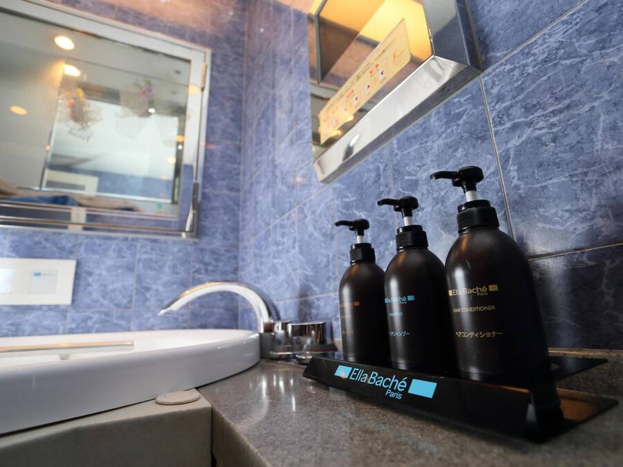 Une salle de bain équipée d’un lavabo, d’un miroir et de trois flacons d’après-shampoing Ella Bache.