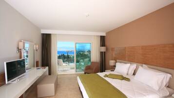 Ein Hotelzimmer mit Bett, Fernseher, Schreibtisch und Balkon mit Blick.