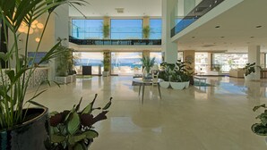 A spacious lobby with a high ceiling, multiple seating areas, and large windows offering views of the sea. - Sentido Bellazure (Bodrum)