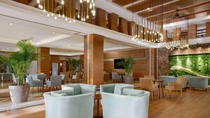 A spacious lobby with modern furniture, a large aquarium, and a high ceiling with hanging lights.