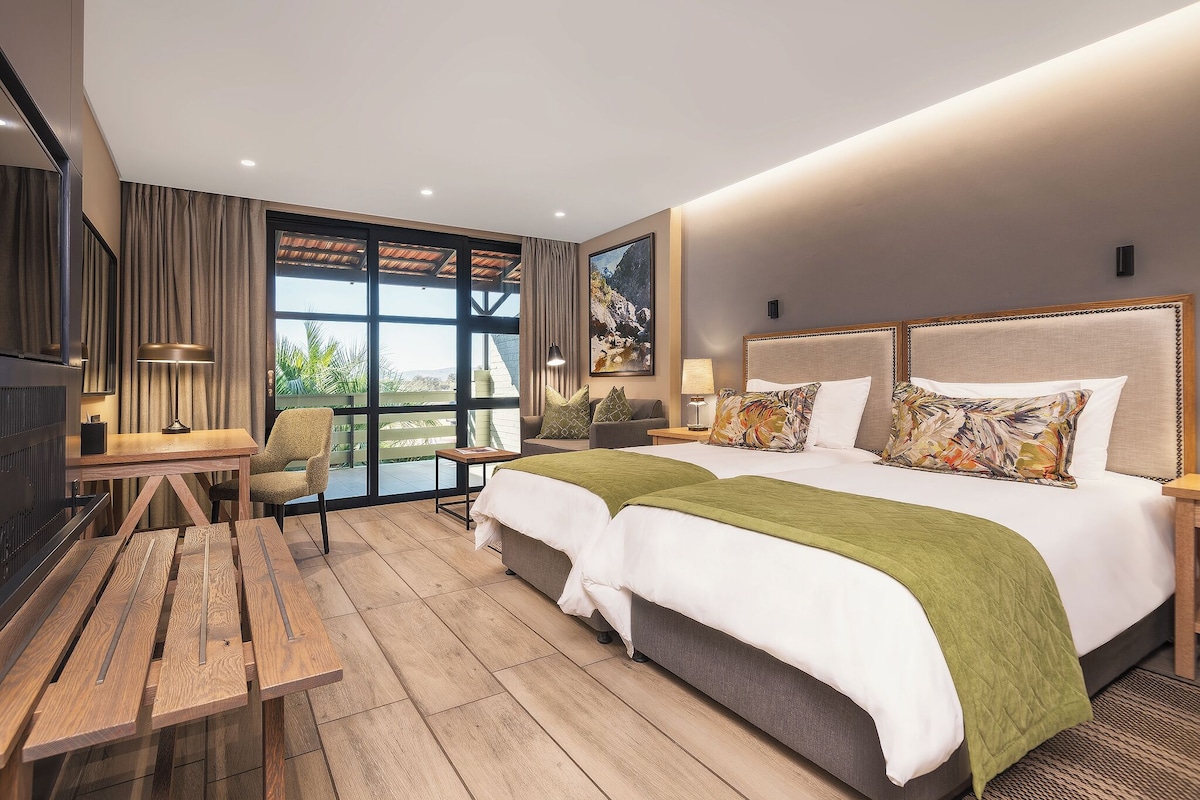 A modern hotel room with a large bed, a desk, and a chair.